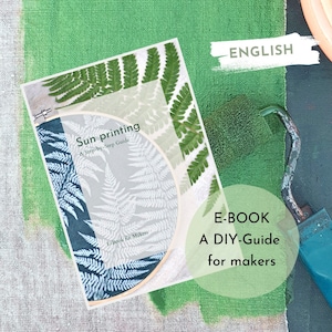 Könnte beinhalten: Ein E-Book mit dem Titel "Sun printing: A Step-by-Step Guide" mit Farnblatt-Illustrationen. Das Cover befindet sich auf einer grün gestrichenen Oberfläche mit einer Farbrolle. Der Text auf dem Cover lautet "E-BOOK A DIY-Guide for makers".