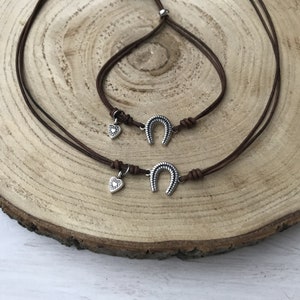May include: Two brown leather cord bracelets with silver horseshoe charms and small heart charms.