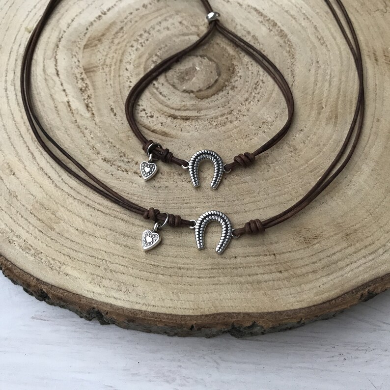 May include: Two brown leather cord bracelets with silver horseshoe charms and small heart charms.