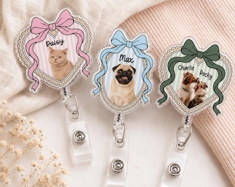 May include: Three heart-shaped badge reels featuring custom pet portraits. The first shows a cat named Daisy with a pink bow, the second a pug named Max with a blue bow, and the third two dogs named Charlie and Rocky with a green bow.