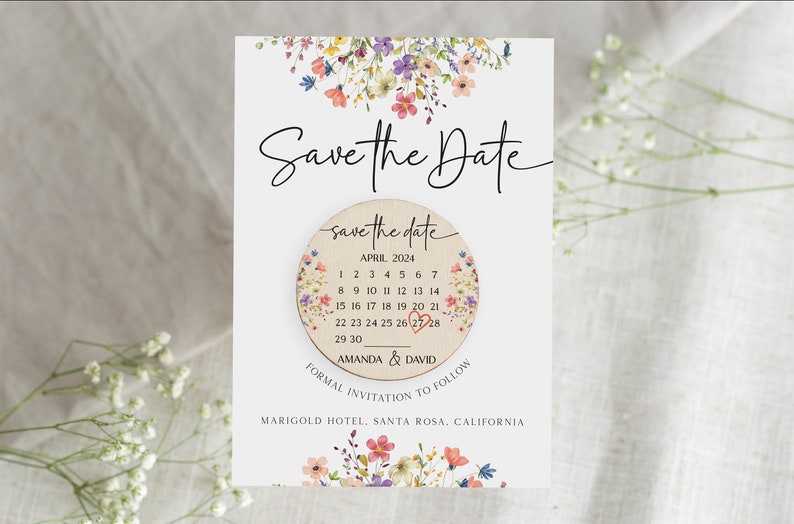Puede incluir: Tarjeta de guardar la fecha con un dise&ntilde;o floral. La tarjeta presenta un c&iacute;rculo de madera con un calendario que muestra abril de 2024 con un coraz&oacute;n marcando el 26. El texto "save the date" est&aacute; escrito en el c&iacute;rculo, junto con los nombres "Amanda & David". La tarjeta tambi&eacute;n incluye el texto "Invitaci&oacute;n formal a seguir" y la ubicaci&oacute;n "Marigold Hotel, Santa Rosa, California."