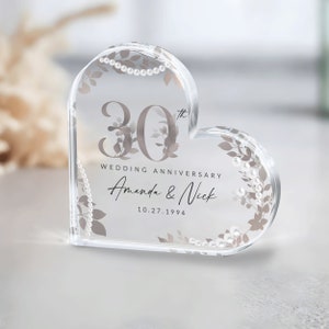 May include: A clear heart-shaped crystal paperweight with a 30th wedding anniversary design. The design features a floral pattern with pearl accents and the text "30th Wedding Anniversary Amanda & Nick 10.27.1994".