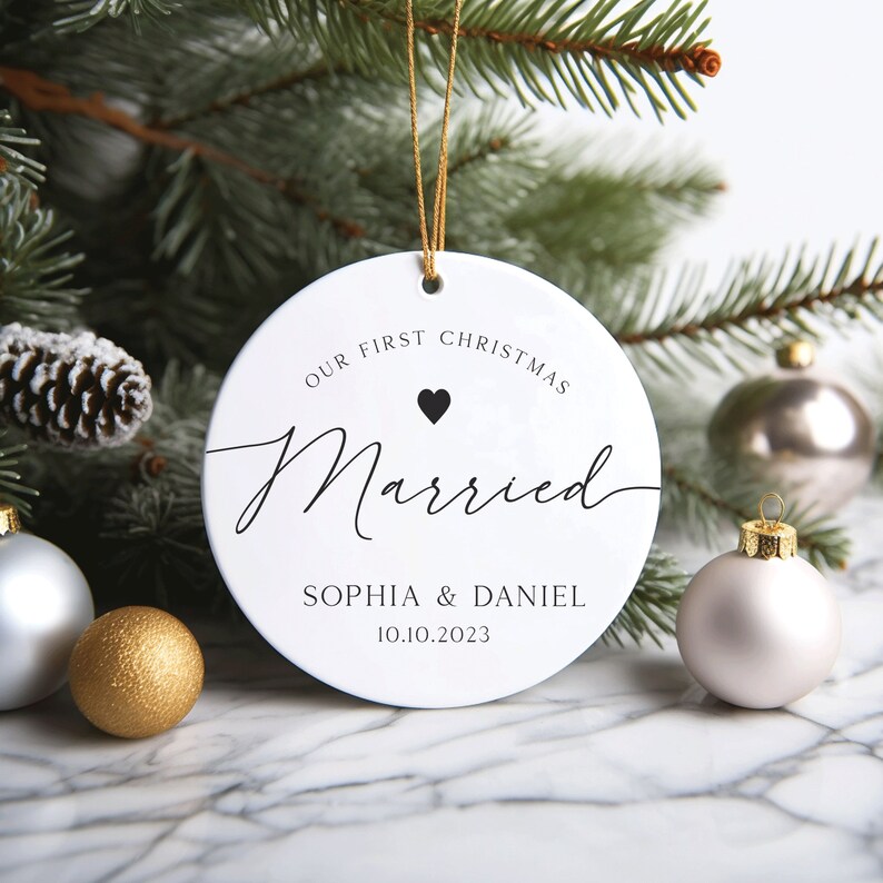 May include: White round Christmas bauble with the text "Our First Christmas Married" and a small black heart. Below the text is "Sophia & Daniel 10.10.2023".