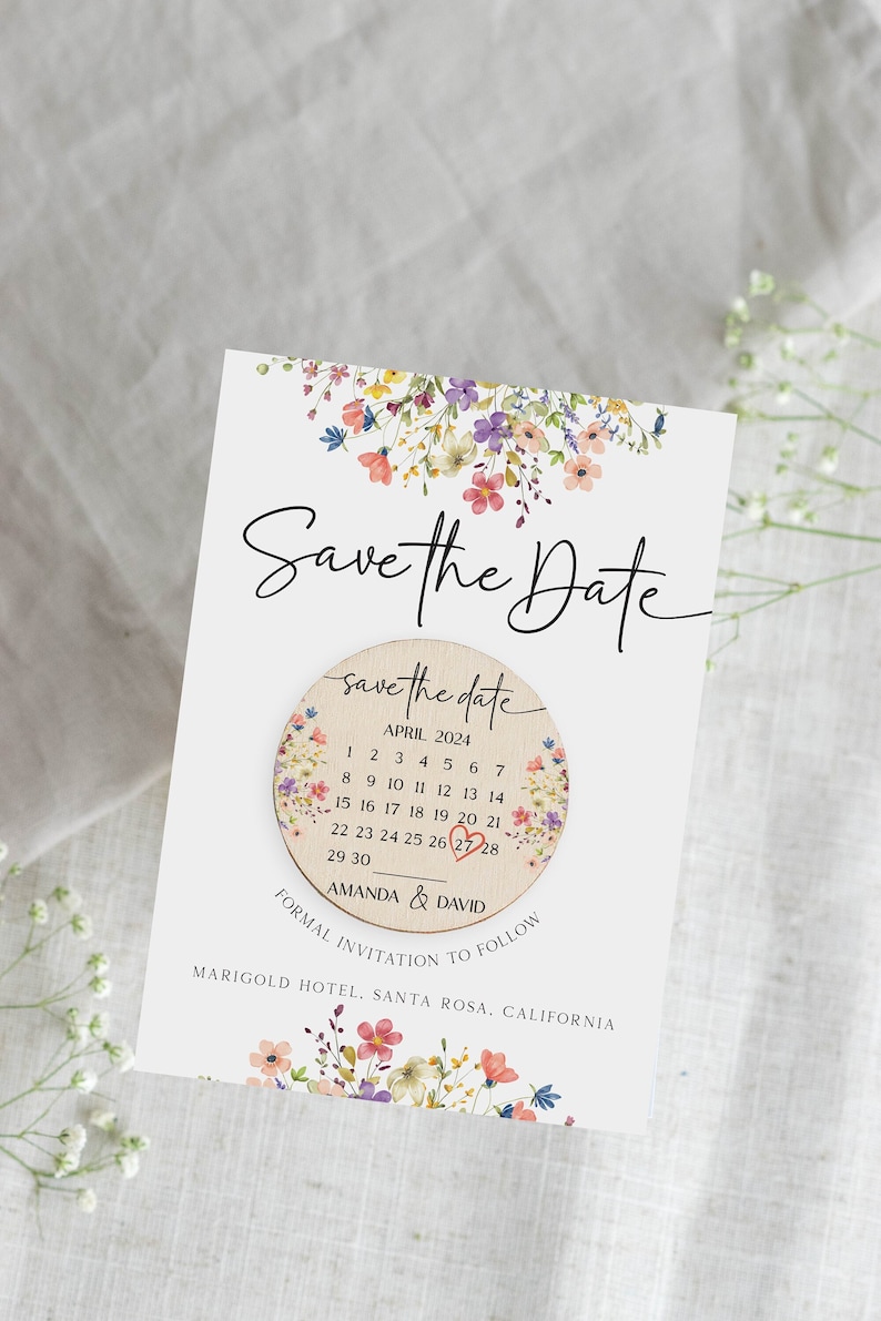 Puede incluir: Tarjeta de "Save the Date" con un dise&ntilde;o floral. La tarjeta presenta un c&iacute;rculo de madera con un calendario para abril de 2024, con el 27 encerrado en rojo. El texto "Amanda & David" est&aacute; debajo del calendario. La tarjeta tambi&eacute;n incluye el texto "Invitaci&oacute;n formal a seguir" y "Marigold Hotel, Santa Rosa, California."