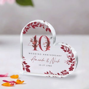 May include: A clear heart-shaped acrylic paperweight with a red and white floral design. The number 40 is in the center with the text "Wedding Anniversary Amanda & Nick 10.27.1984".