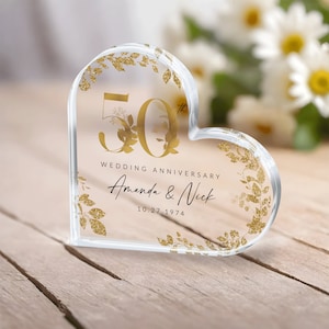 May include: A clear heart-shaped crystal paperweight with gold glitter and floral accents. The number 50 is prominently displayed, along with the text "Wedding Anniversary Amanda & Nick 10.27.1974".