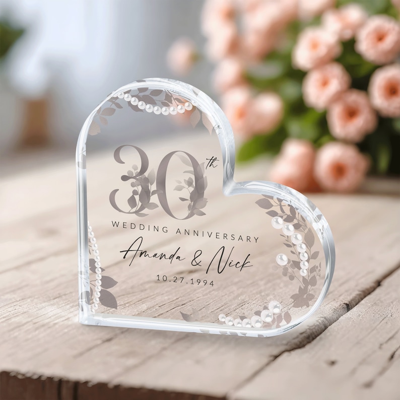 May include: A clear heart-shaped crystal paperweight with a floral design and the text "30th Wedding Anniversary Amanda & Nick 10.27.1994".