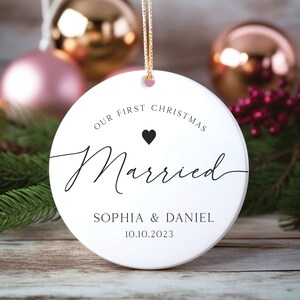 May include: White round Christmas bauble with the text "Our First Christmas Married" and a black heart. Below the text is "Sophia & Daniel 10.10.2023".
