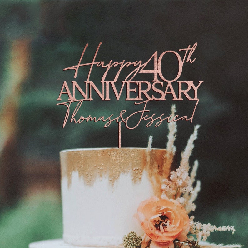 May include: Rose gold cake topper with the text "Happy 40th Anniversary Thomas & Jessica".