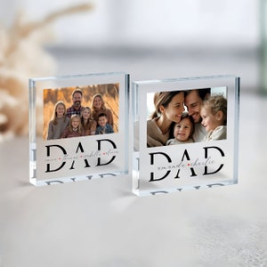 May include: Two clear glass photo blocks with the word "DAD" in black lettering. Each block features a different family photo and the names of the children in cursive script below the word "DAD".