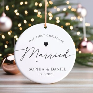 May include: White round Christmas bauble with the text "Our First Christmas Married" and a small black heart. Below the text is "Sophia & Daniel 10.10.2023".