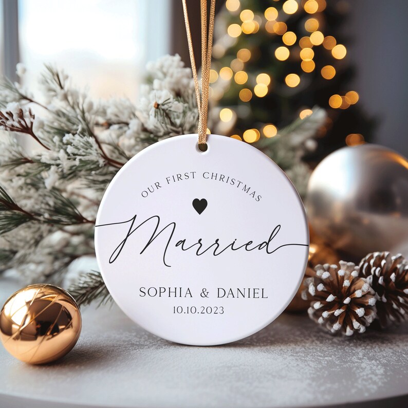 May include: White round Christmas bauble with the text "Our First Christmas Married" and a small black heart. Below the text is "Sophia & Daniel 10.10.2023".