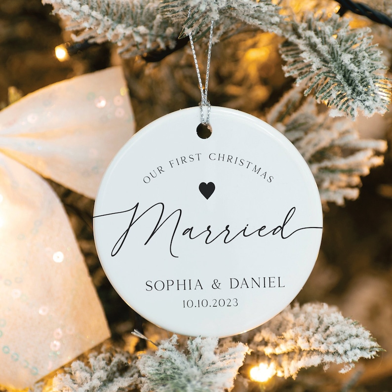 May include: White ceramic Christmas bauble with black text that reads "Our First Christmas Married Sophia & Daniel 10.10.2023" with a small black heart above the word "Married".