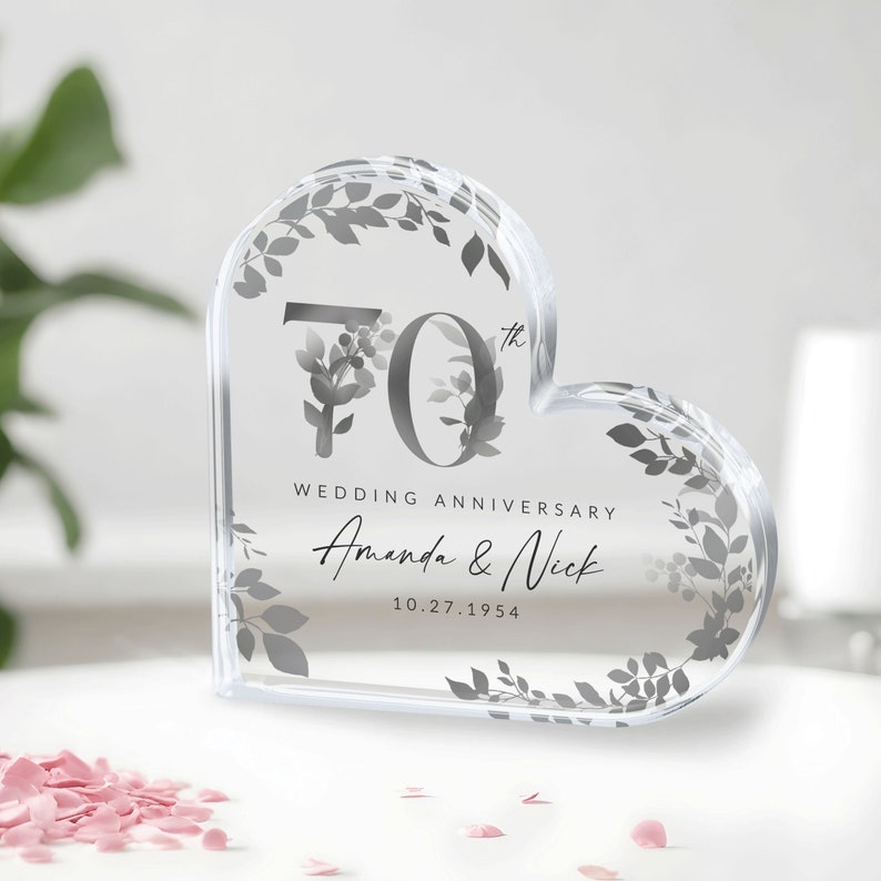 May include: A clear heart-shaped crystal paperweight with a floral design and the text "70th Wedding Anniversary Amanda & Nick 10.27.1954"