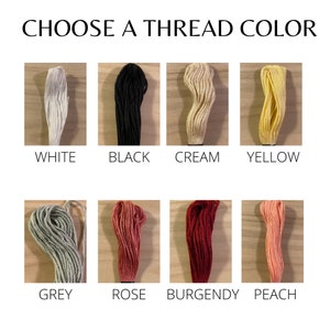 May include: A selection of embroidery floss in various colors, including white, black, cream, yellow, grey, rose, burgundy, and peach.  Choose a thread color.