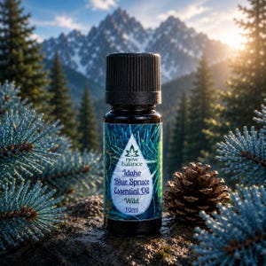 Puede incluir: Un frasco pequeño de vidrio oscuro de aceite esencial New Balance Idaho Blue Spruce con tapa negra estriada. La etiqueta presenta una forma de gota blanca con el texto New Balance, Idaho Blue Spruce Essential Oil, Wild y 10ml impreso.