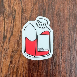 May include: A white sticker with a black outline of a red liquid in a bottle. The bottle has a cap and the text "© 2022 MADISON LTD" is printed on the sticker.