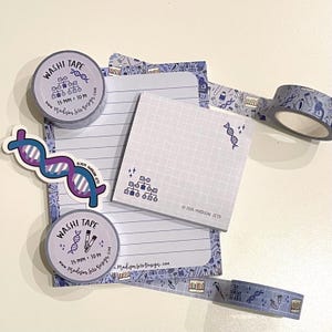 May include: A collection of science-themed stationery items, including washi tape rolls, a sticker, and notepads. The tape is 15 mm wide and 10 m long, featuring a repeating pattern of lab equipment and DNA strands. The sticker and notepads have a DNA strand graphic.