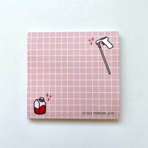 Könnte beinhalten: Ein quadratischer, rosa karierter Notizblock mit Illustrationen einer Sprühflasche und einer Flüssigkeitsflasche. Die Sprühflasche ist weiß und rot, und die Flüssigkeitsflasche ist rot. Der Notizblock trägt den Text "© 2022 MADISON SETO".