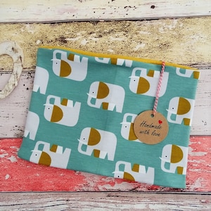 Könnte beinhalten: Eine türkisfarbene Stofftasche mit einem sich wiederholenden Muster aus weißen Elefanten mit goldenen Akzenten. Die Tasche hat eine gelbe Innenseite und ein Etikett mit der Aufschrift "Handmade with love".