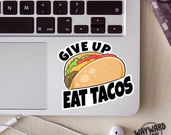 May include: A die-cut sticker featuring a cartoon taco with a light brown shell, green lettuce, red tomatoes, and brown meat. The text "GIVE UP" is arched in black above the taco, and "EAT TACOS" is written in bold black letters below the taco.