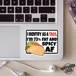 May include: A white sticker with black text and a cartoon taco. The text reads "I identify as a taco. I'm 73% fat and spicy AF."