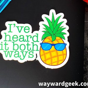 May include: A white sticker with a green pineapple wearing blue sunglasses and the text "I've heard it both ways".