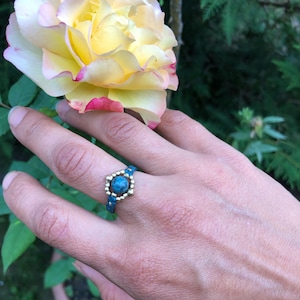 May include: A turquoise gemstone ring with gold beads and a beaded band.
