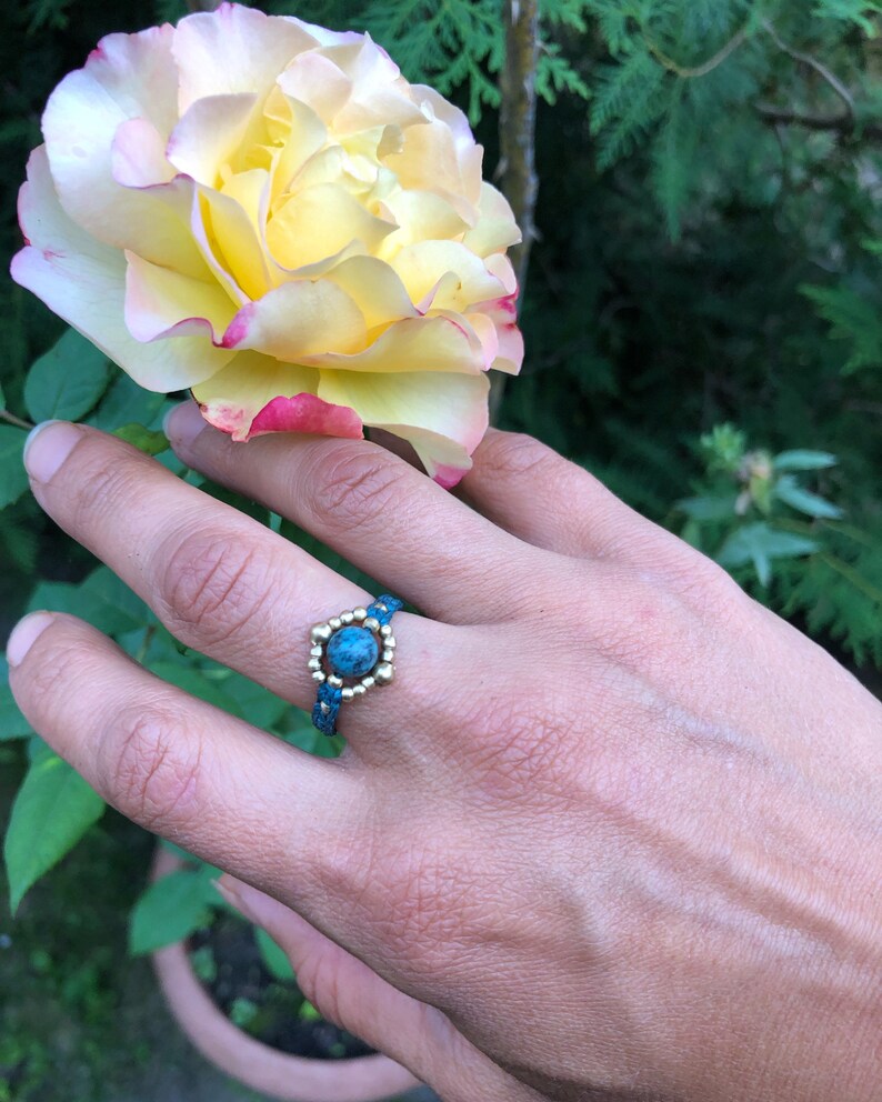 May include: A turquoise gemstone ring with gold beads and a beaded band.