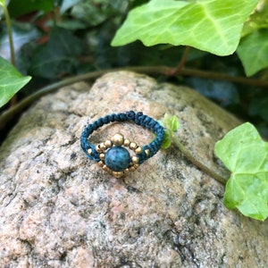 May include: A teal blue ring with a green stone and gold beads.