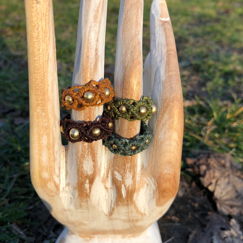 May include: Four crocheted rings with brass beads in shades of brown and green.