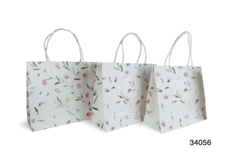 K&ouml;nnte beinhalten: Drei wei&szlig;e Papiert&uuml;ten mit Blumendruck und Kordelgriffen. Die Taschen sind unterschiedlich gro&szlig; und in einer Reihe vom gr&ouml;&szlig;ten zum kleinsten angeordnet.