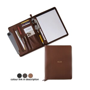 May include: A brown leather zippered portfolio with a notepad, pen holders, and card slots. The portfolio is open to reveal the interior and has the initials "MJM" embossed on the front.