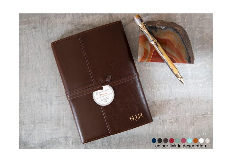 Puede incluir: Un diario de cuero marr&oacute;n con un monograma dorado en relieve "H.J.H." y una etiqueta blanca con la palabra "Truth" en ella. El diario est&aacute; atado con una correa de cuero marr&oacute;n.