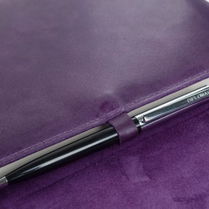 May include: A purple leather notebook with a silver pen inside. The pen has the word "DIPLOMAT" printed on it.