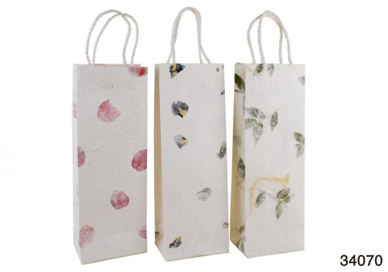 K&ouml;nnte beinhalten: Drei wei&szlig;e Papiert&uuml;ten mit Henkeln. Die Taschen haben verschiedene Blumenmuster: rosa Bl&uuml;tenbl&auml;tter, blaue und gelbe Blumen und gr&uuml;ne Bl&auml;tter.