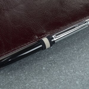 Puede incluir: Un bol&iacute;grafo plateado con un cuerpo negro y una banda blanca y negra. El bol&iacute;grafo est&aacute; grabado con la palabra "Diplomat".