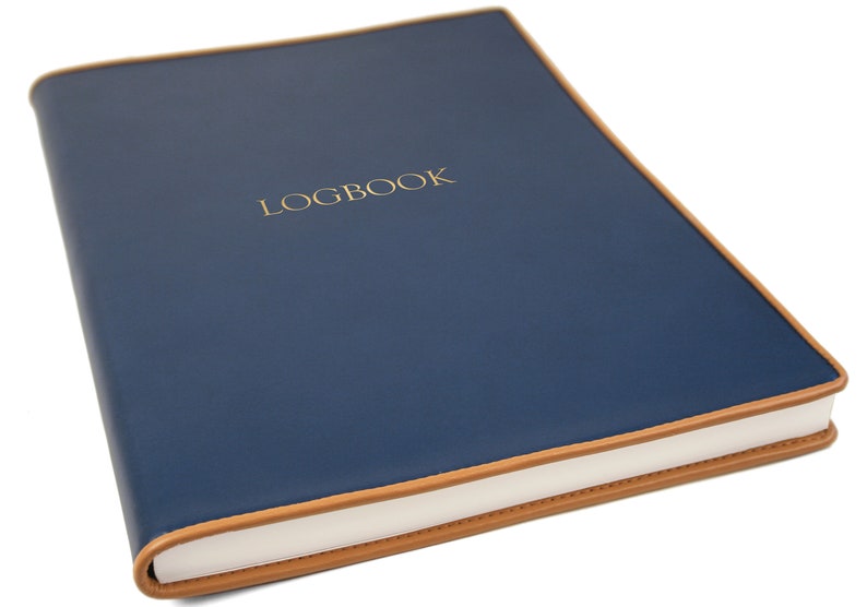 May include: A navy blue leather-bound logbook with a tan leather trim and the word "LOGBOOK" embossed in gold on the front cover.