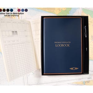 May include: A navy blue logbook with the name "Thomas Topoliatis" and the word "LOGBOOK" in gold lettering. The logbook is in a black box with a pen. The text "colour link in description free pen engraving!" is at the top.