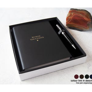 Op de afbeelding: Een zwart notitieboek met de gouden tekst "WORDS THOUGHTS", een zilveren en zwarte pen en een decoratieve steen in een zwart-witte geschenkdoos. Deze geschenkset is ideaal voor schrijvers en mensen die van journalen houden.