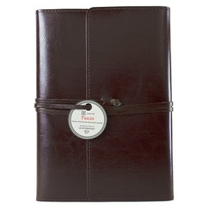 Puede incluir: Un diario de cuero marr&oacute;n con una correa de cuero y una etiqueta que dice "Tuscan Italian Handmade Recycled Leather Journal by Leatherbound".