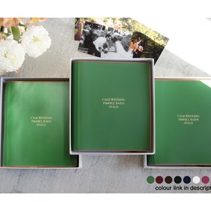May include: Three green leather-bound wedding albums with gold trim and the text "C&M Wedding Pimhill Barn 09.10.21" on the front.