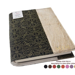 May include: A journal featuring a black and gold floral patterned cover and a light-coloured, textured section. The journal has a stitched border and the initials "MJM" in gold. The label reads "Sari Life Art".