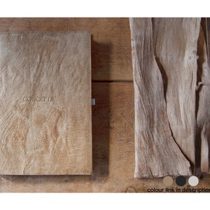 May include: A rectangular notebook with a textured light brown cover featuring the word CONCEPTS embossed in the centre. Beside the notebook lies a matching piece of textured light brown material. Three small circular colour swatches are below.