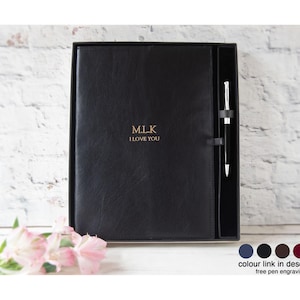May include: A black notebook with a smooth cover featuring the gold embossed text M.L.K and I LOVE YOU. The notebook is housed in a matching black presentation box with a dedicated side slot containing a black and silver ballpoint pen.