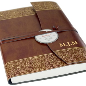 May include: A brown leather journal with gold embossed detailing and a leather strap closure. The journal has a label that reads "Romano" and is personalized with the initials "M.J.M."