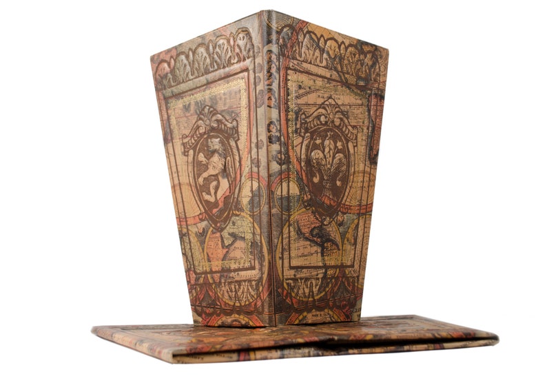 May include: A vintage-style, decorative box with a hinged lid. The box is made of cardboard and features a brown, beige, and orange patterned design with ornate details. The box is closed and the lid is slightly ajar.