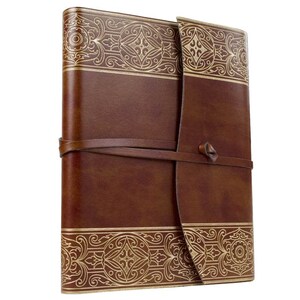 May include: A brown leather-bound journal with a gold embossed design. The journal has a strap closure and is perfect for writing or sketching.