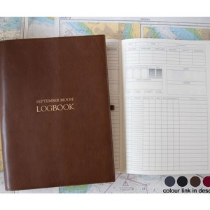 May include: Brown leather bound logbook with the title "SEPTEMBER MOON LOGBOOK" embossed in gold on the front cover. The logbook is open to a blank page with columns for recording data.