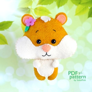 May include: A felt hamster sewing pattern with a flower on its head. The pattern is for a small, cute hamster with a white belly and orange fur. The pattern is available as a PDF download.